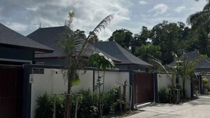 Un quartier résidentiel avec des maisons, une entrée sécurisée et une végétation luxuriante.