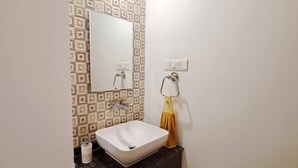 A bathroom with a white sink, dark cabinets, patterned wall tiles, and a mirror. - Casa Nadella (Alto de Porvorim)