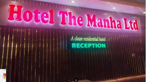 Un cartell d'hotel amb la inscripció "Hotel The Manha Ltd" i un senyal de neó que diu "RECEPCIÓ".