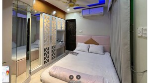 Un dormitori modern amb llit, ventilador de sostre i armari amb separador decoratiu.