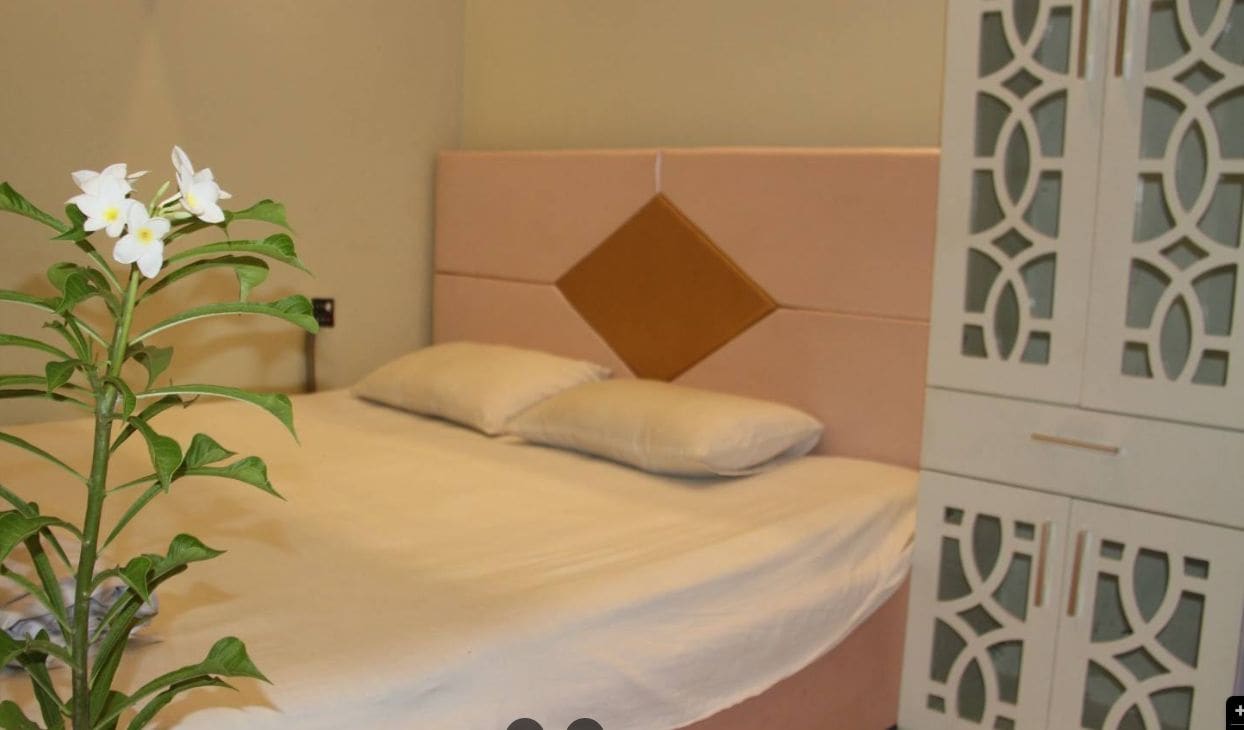 Une chambre à coucher avec un lit, une tête de lit décorative et une armoire blanche ornée de motifs complexes.
