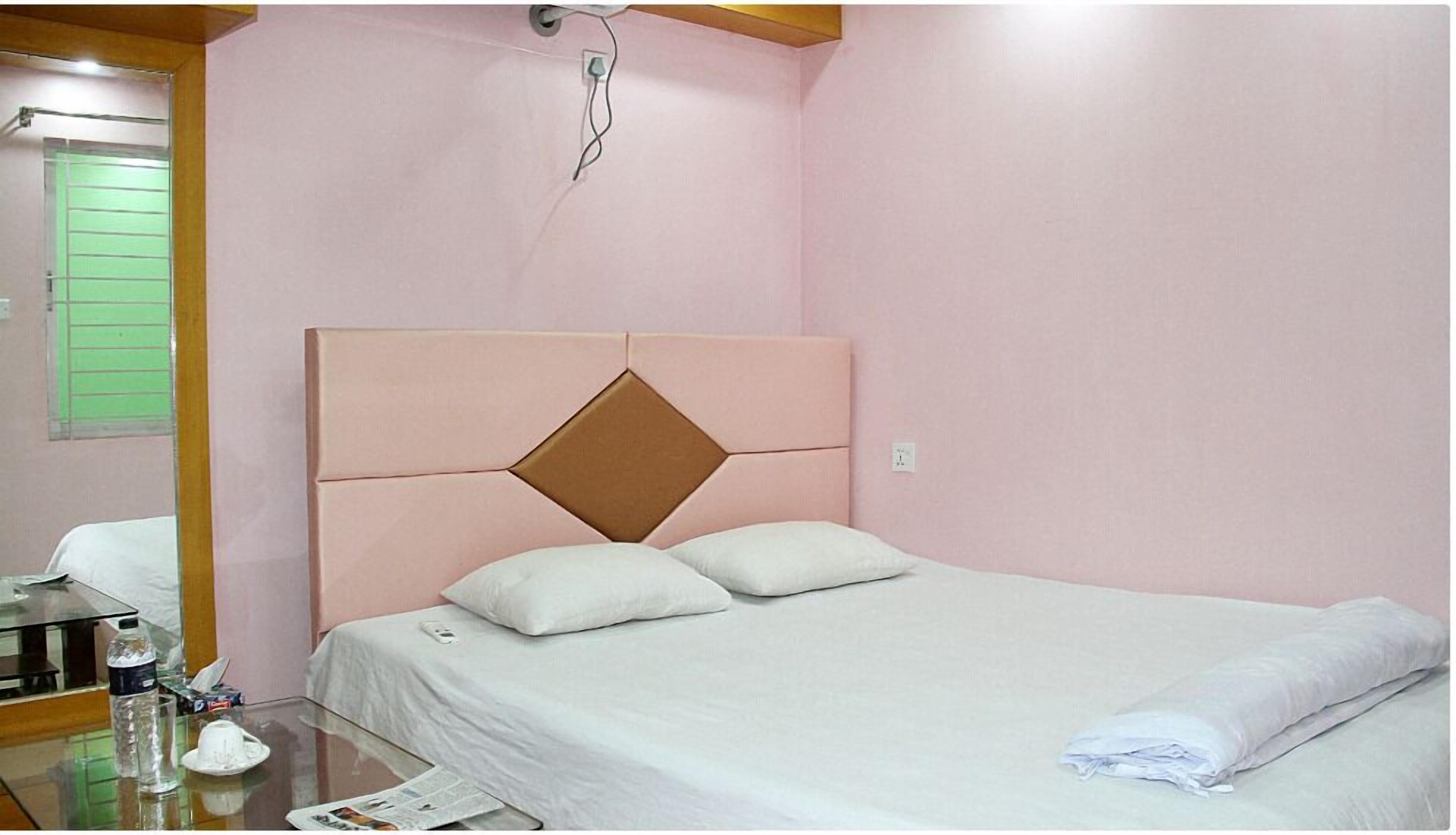 A single bed with a headboard, a bedside table with a lamp, and a mirror on the wall.