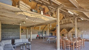 A rustic barn interior with a ping pong table, seating area, and a wooden table with chairs. - Group farmhouse with large garden and wideviews (Elsendorp)