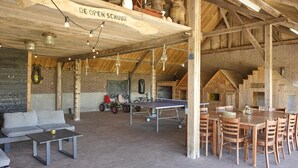 An open-plan space with a ping pong table, seating area, and a lofted ceiling with exposed beams. - Group farmhouse with large garden and wideviews (Elsendorp)