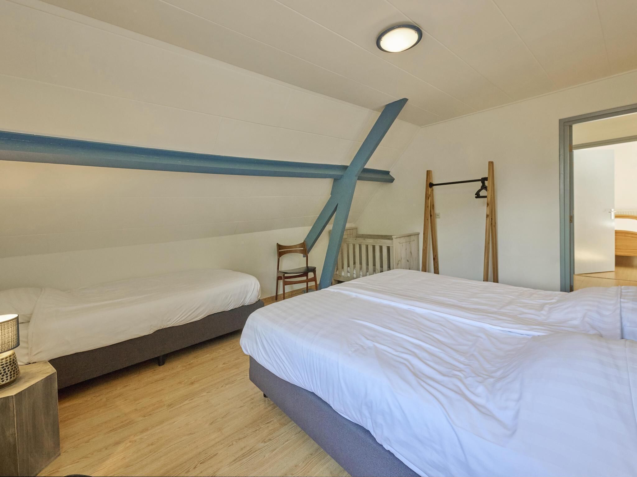 A bedroom with two beds, a wooden floor, a ceiling light, and a window.