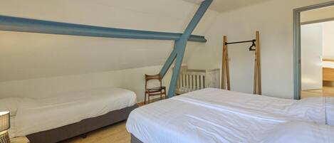 A bedroom with two beds, a wooden floor, a ceiling light, and a window.