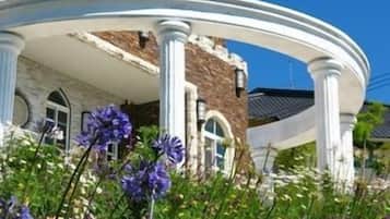 A building with a white porch supported by columns, surrounded by flowers.