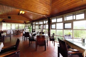 A covered dining area with wooden ceiling and large windows, furnished with tables and chairs. - Liching Garden Village (Nantou)