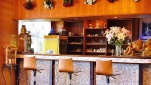 A bar area with three stools, a counter with various items, and shelves with decorative objects. - Liching Garden Village (Nantou)