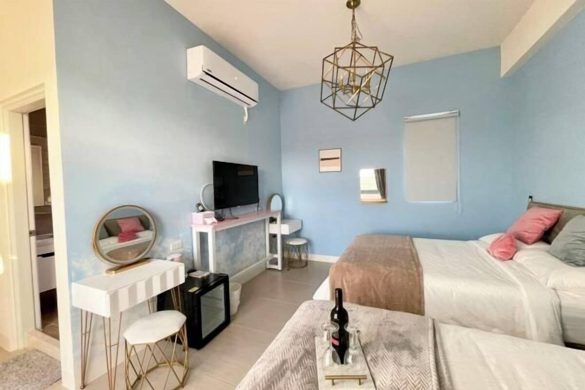 A bedroom with a bed, a desk, a chair, a TV, and a mirror.