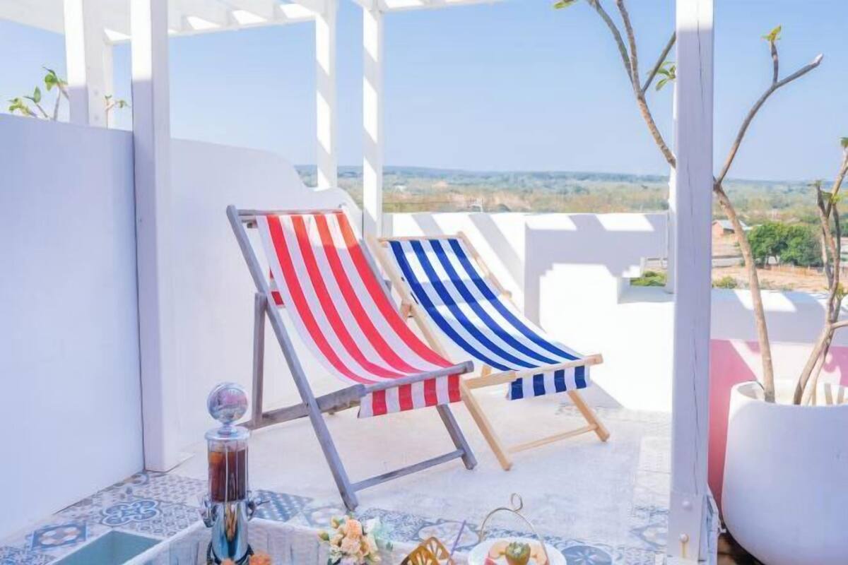 Two striped lounge chairs on a balcony with a clear view of the landscape.