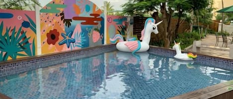 Una piscina con murales coloridos en las paredes, un flotador de unicornio y un patito inflable.