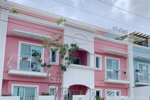 A multi-story building with balconies, a red archway, and a white fence. - Pinky Promise Villa (Pingtung)