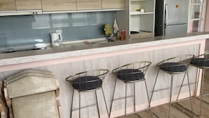 A kitchen with wooden cabinets, a marble countertop, and a stainless steel refrigerator. - Pinky Promise Villa (Pingtung)