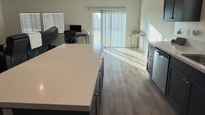 A modern kitchen with a large island, dark cabinetry, and a dining area with a table and chairs. - 5-bedroom House in Marvelous Winchester with AC/Heater (Winchester)