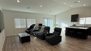 A spacious living area with a large sofa set, a coffee table, and a kitchen area with a bar. - 5-bedroom House in Marvelous Winchester with AC/Heater (Winchester)
