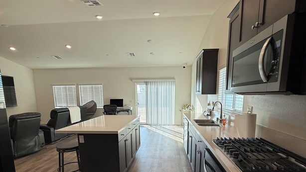 A modern kitchen with a central island, dark cabinetry, and a stainless steel range hood. - 5-bedroom House in Marvelous Winchester with AC/Heater (Winchester)