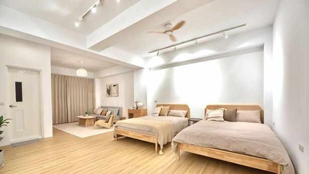 A modern bedroom with two beds, a ceiling fan, and a large window. - Sun eden (Nantou)
