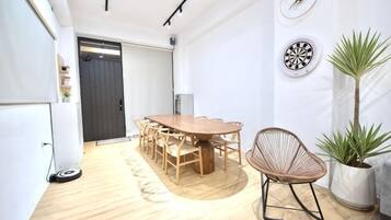 Una habitación con una mesa de comedor de madera, sillas, una planta en maceta y un dardo fijado a la pared.