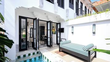 A modern outdoor living area with a pool, a sofa, and a dining area.
