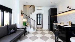 A modern kitchen with a black refrigerator, a marble countertop, and a sink. There is a staircase leading to a second floor. - Villa Martini Beachside 5  (Canggu)