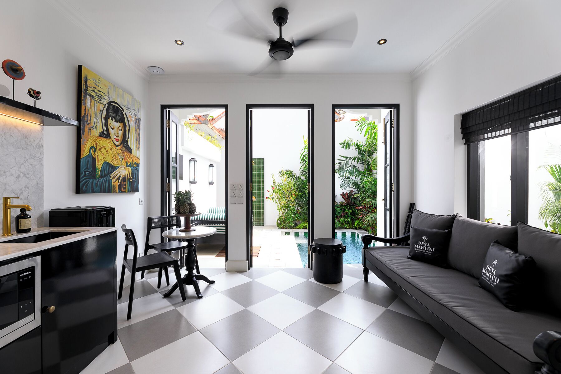 A modern kitchen with a black and white checkered floor, a dining area with a round table and chairs, and a living area with a sofa and a large window.