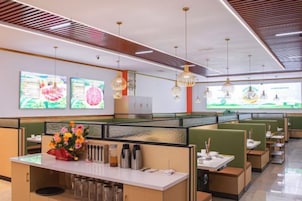 Un restaurante moderno con mesas altas y cabinas, pantallas digitales con el menú y un diseño contempor áneo y limpio.