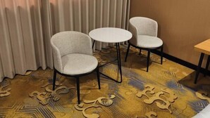 A room with a patterned carpet, two grey upholstered chairs, a small round table, and a wooden partition. - Hongshi Road Branch (Junan County)