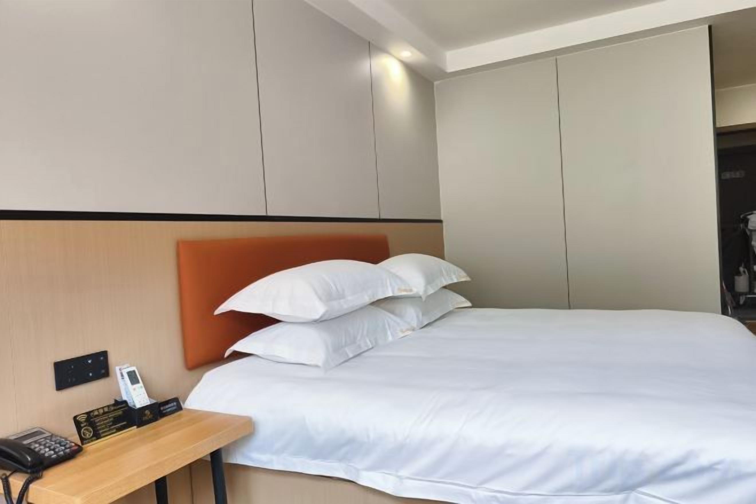 Una camera d'albergo con un letto, un comodino con il telefono e un armadio.
