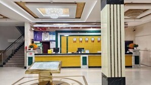 A hotel lobby with a reception desk, a staircase, and a decorative column. - Hongshi Road Branch (Junan County)