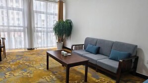 A living room with a sofa, a coffee table, a potted plant, and patterned flooring. - Hongshi Road Branch (Junan County)