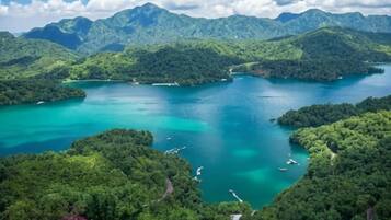Un paysage côtier avec une baie turquoise, bordée de collines et de montagnes verdoyantes.