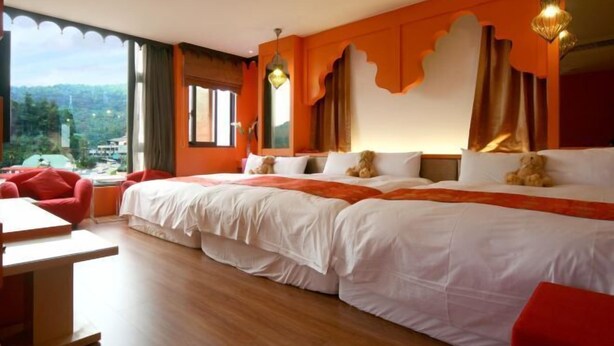Quarto de hotel com uma cama grande, duas mesas de cabeceira, uma escrivaninha e vista para o exterior.