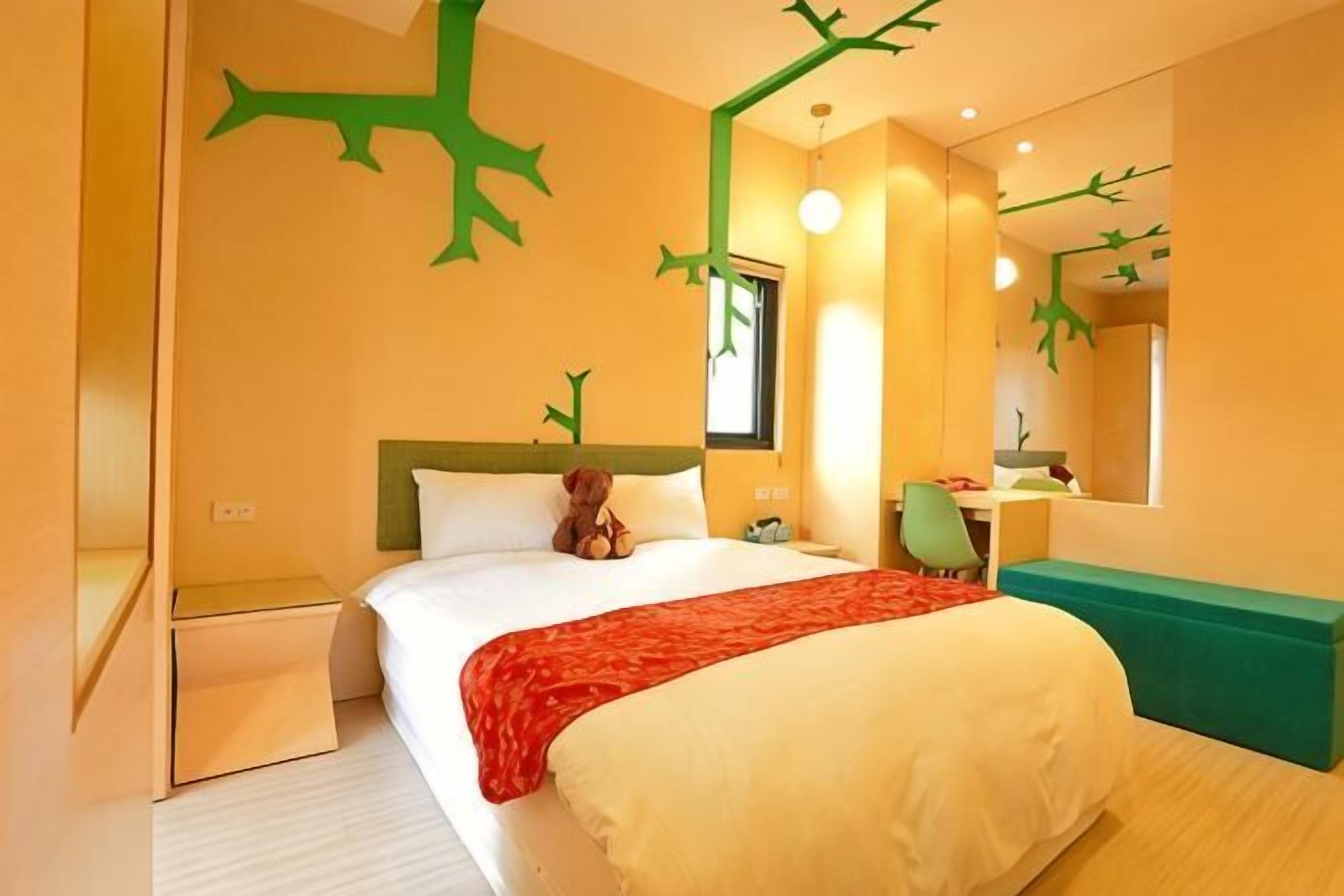 A hotel room with a bed, a desk, a chair, a mirror, and a window.