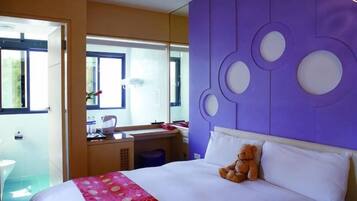 A hotel room with a bed, a desk, a chair, a window, and a bathroom.