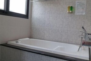 Une salle de bain avec une baignoire, une fenêtre et un mur orné d’un motif géométrique.