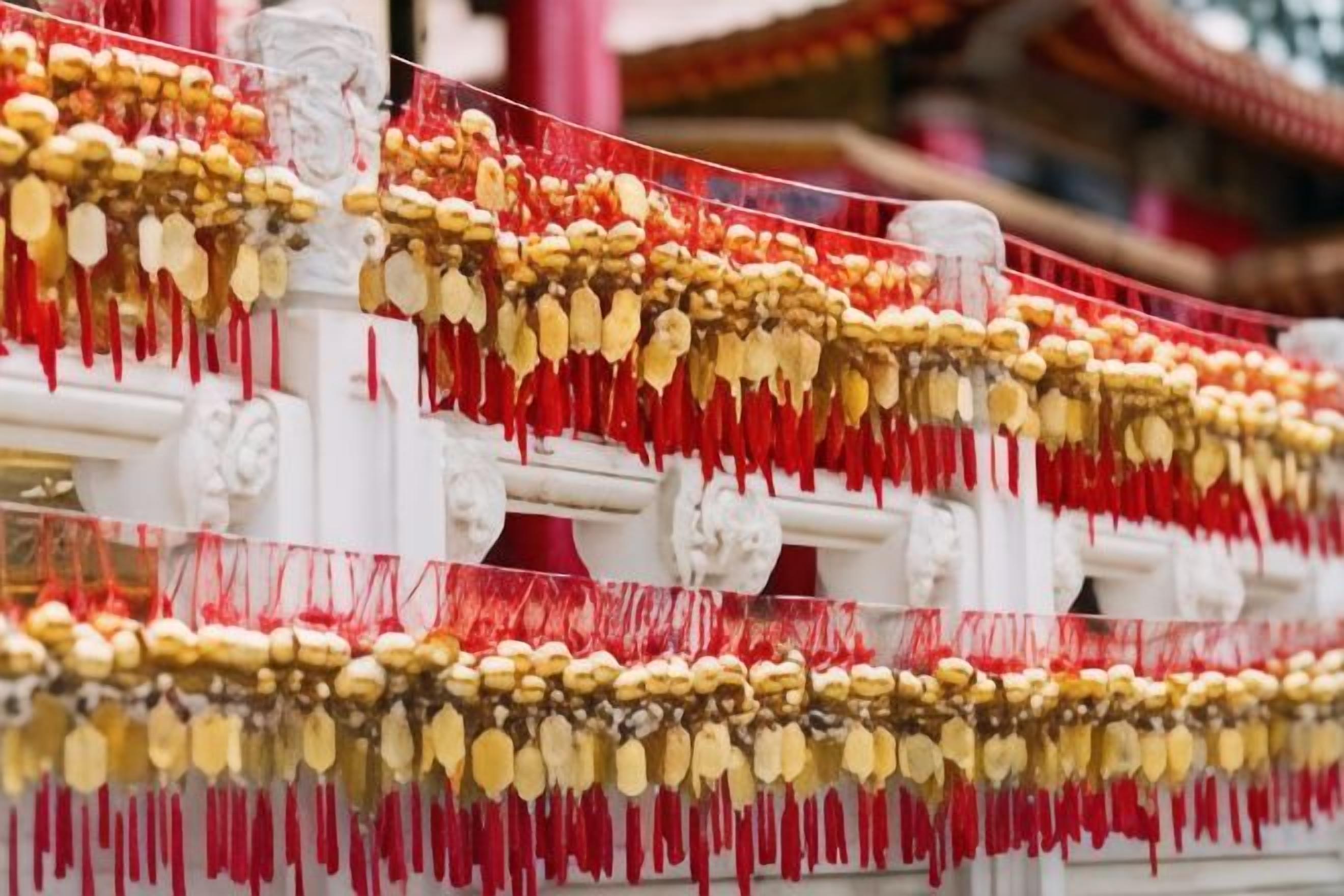 Uma estrutura com vários níveis de colunas brancas, cada uma decorada com pendentes dourados e vermelhos.