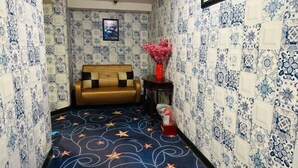 Ein Flur mit strukturierter Tapete, einer Couch, einer Blumenvase und einem Teppich mit Sternenmuster.