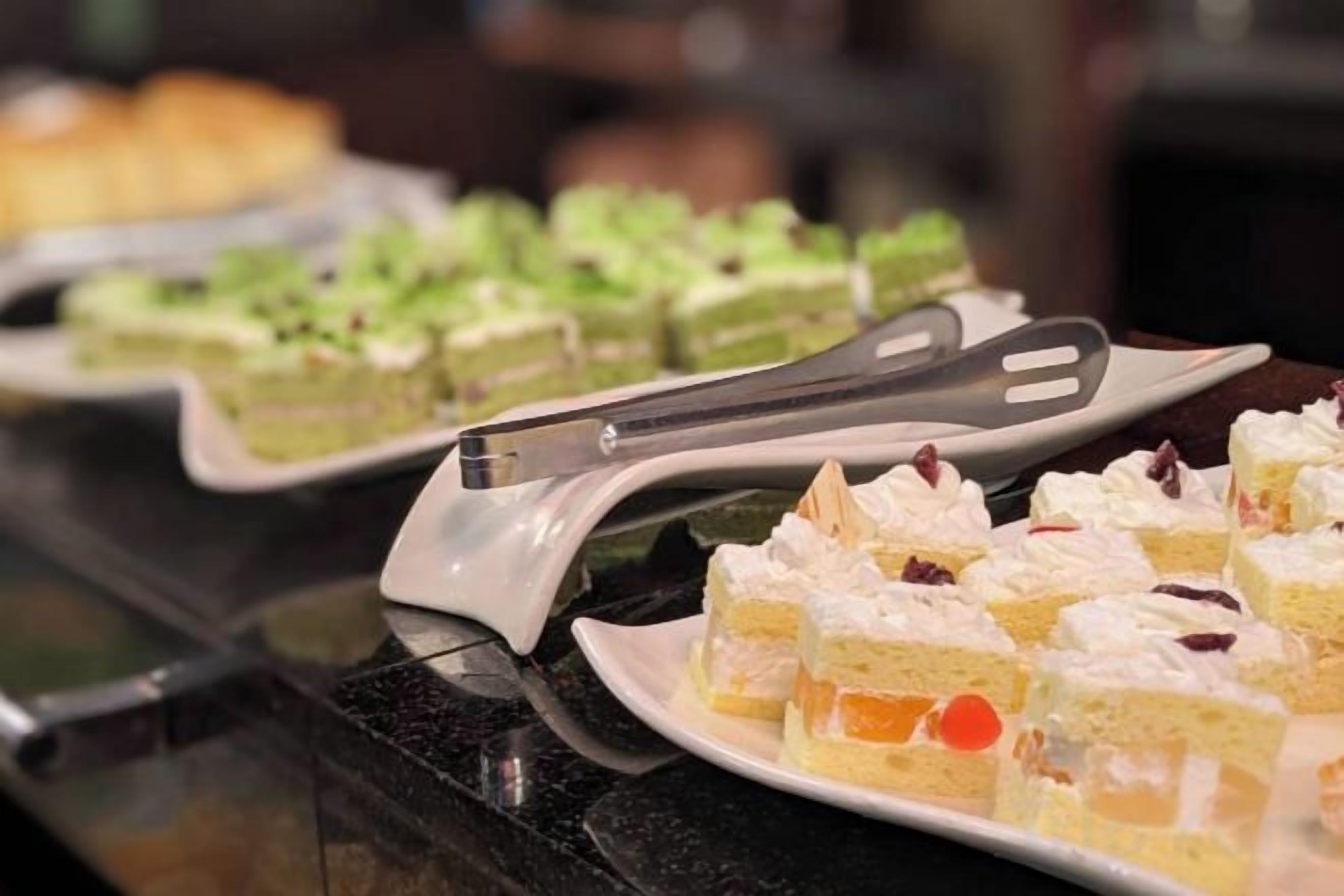 A buffet with various desserts on plates, including cakes and pastries.