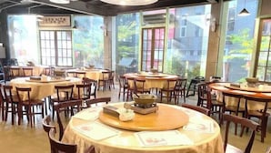 A restaurant with round tables, chairs, and a view of greenery outside. - The M Village (Nantou)