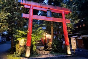 A traditional Japanese torii gate with a signboard, surrounded by greenery and a stone pathway leading to a building. - The M Village (Nantou)