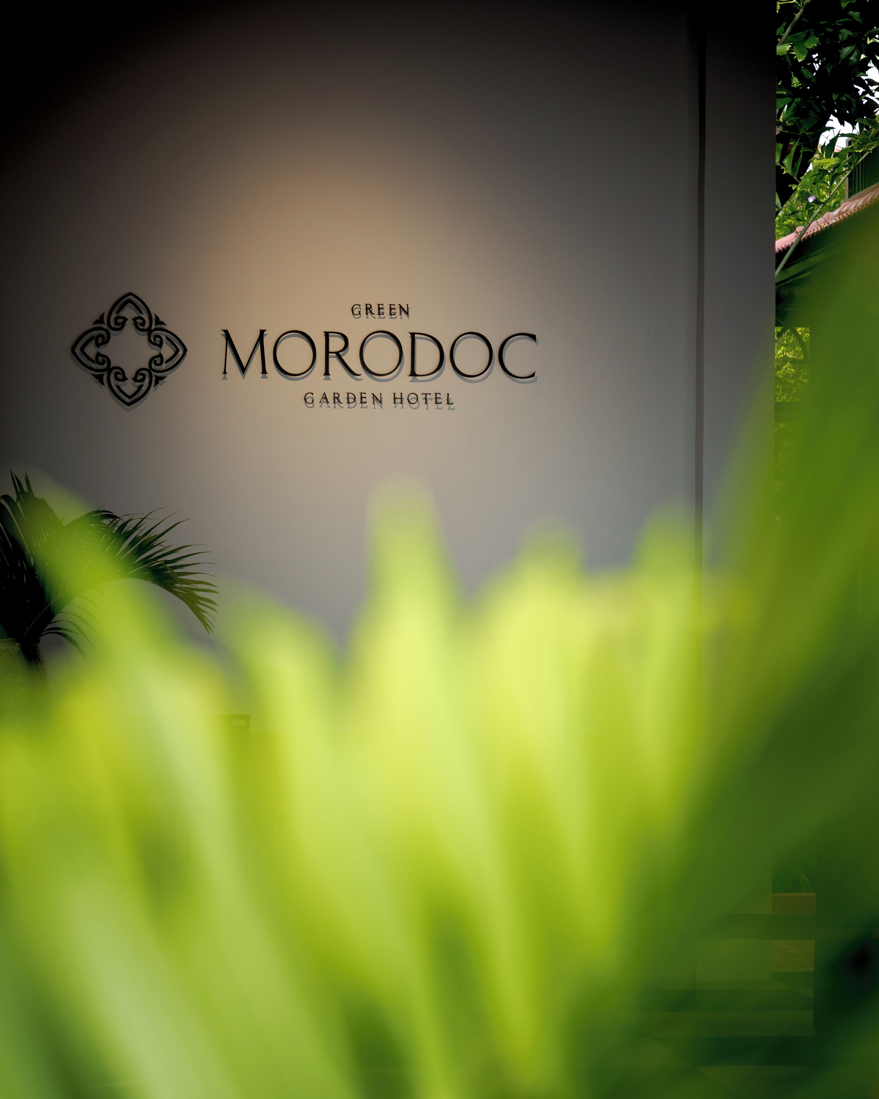 A sign for the Green Morodoc Garden Hotel with a decorative emblem and the hotel's name.