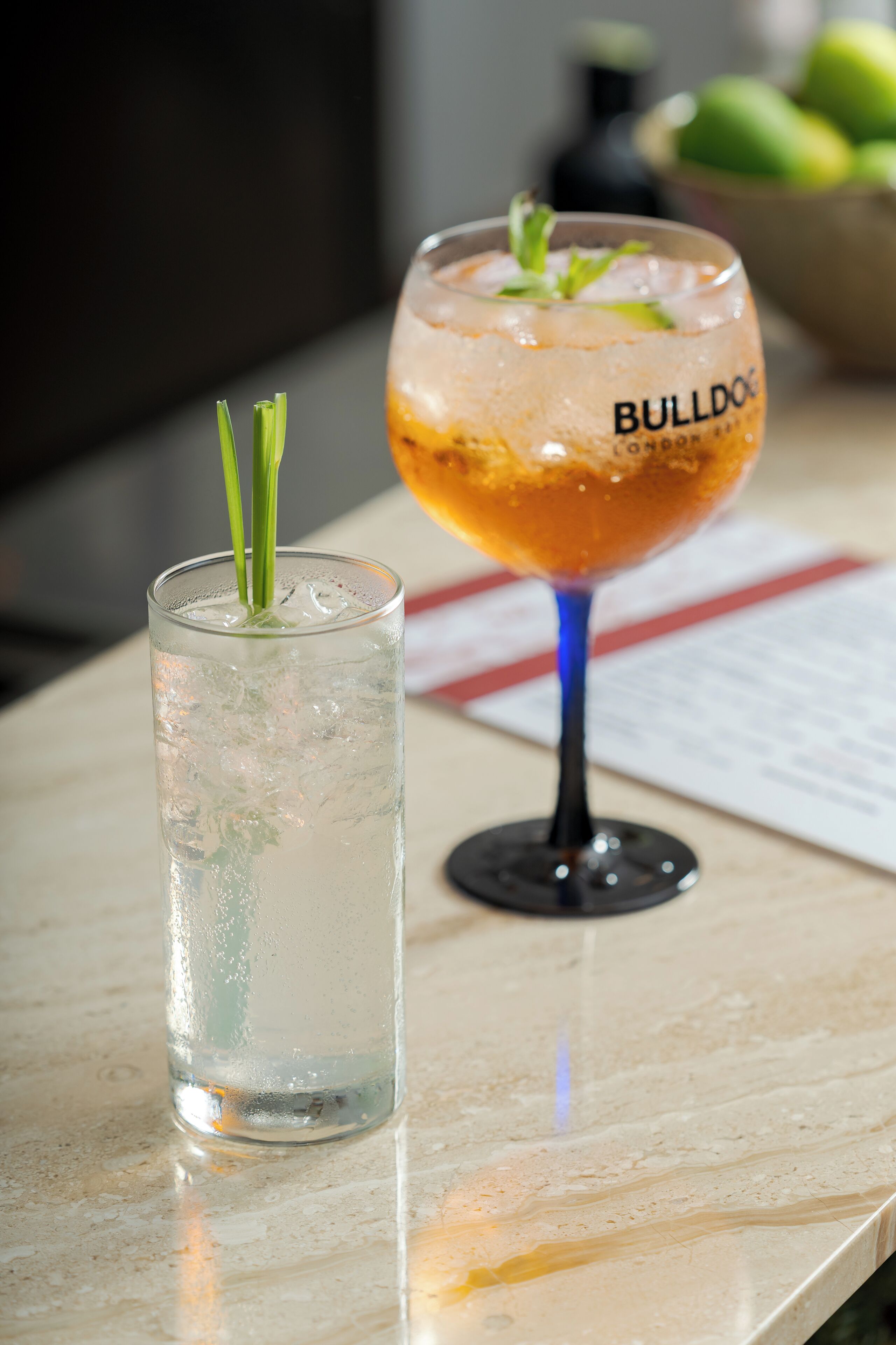Deux verres sur une table, l’un décoré d’une garniture verte et l’autre portant l’étiquette « BULLDOG LONDON ».