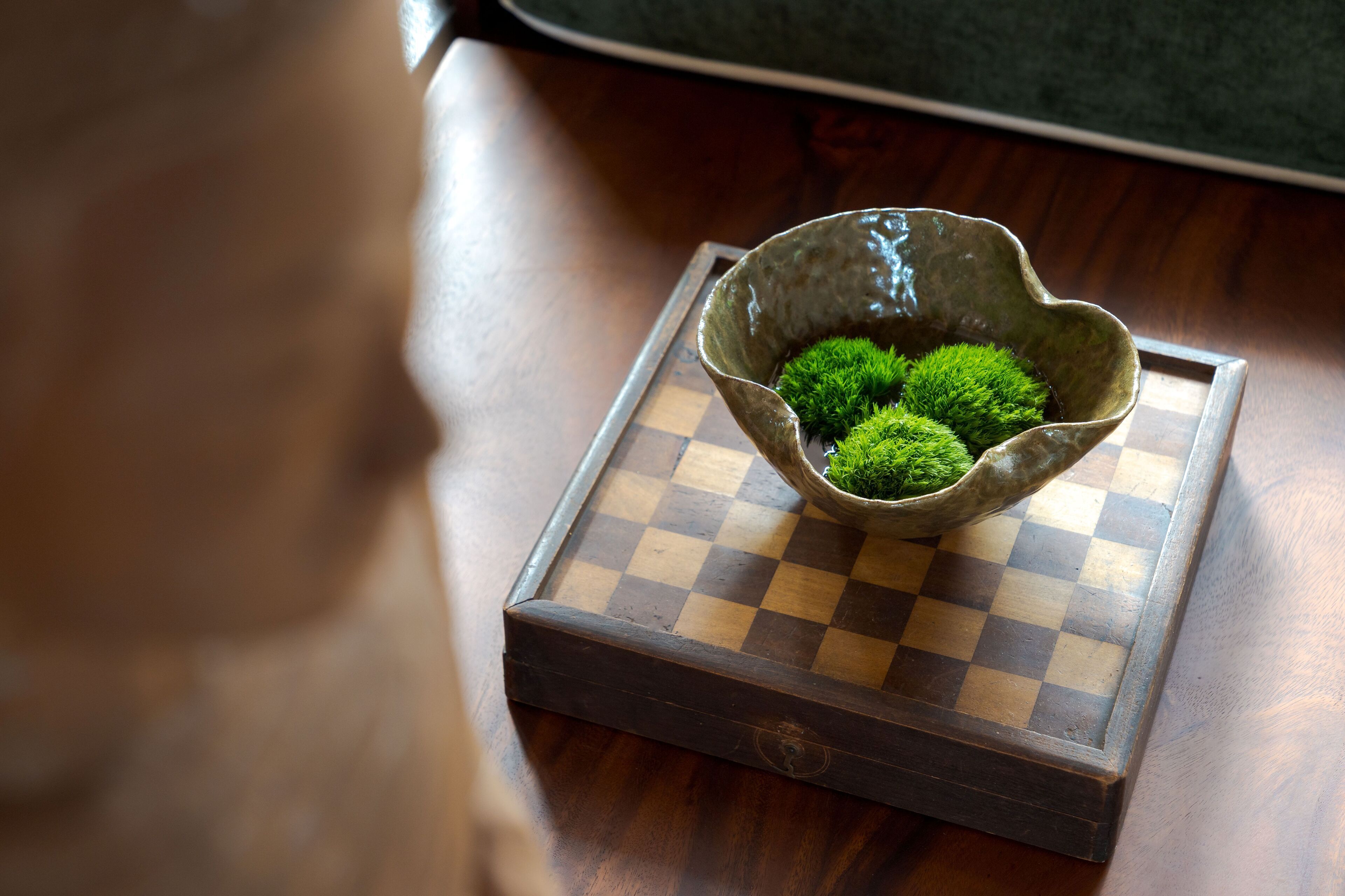 A chessboard with a ceramic bowl containing moss.