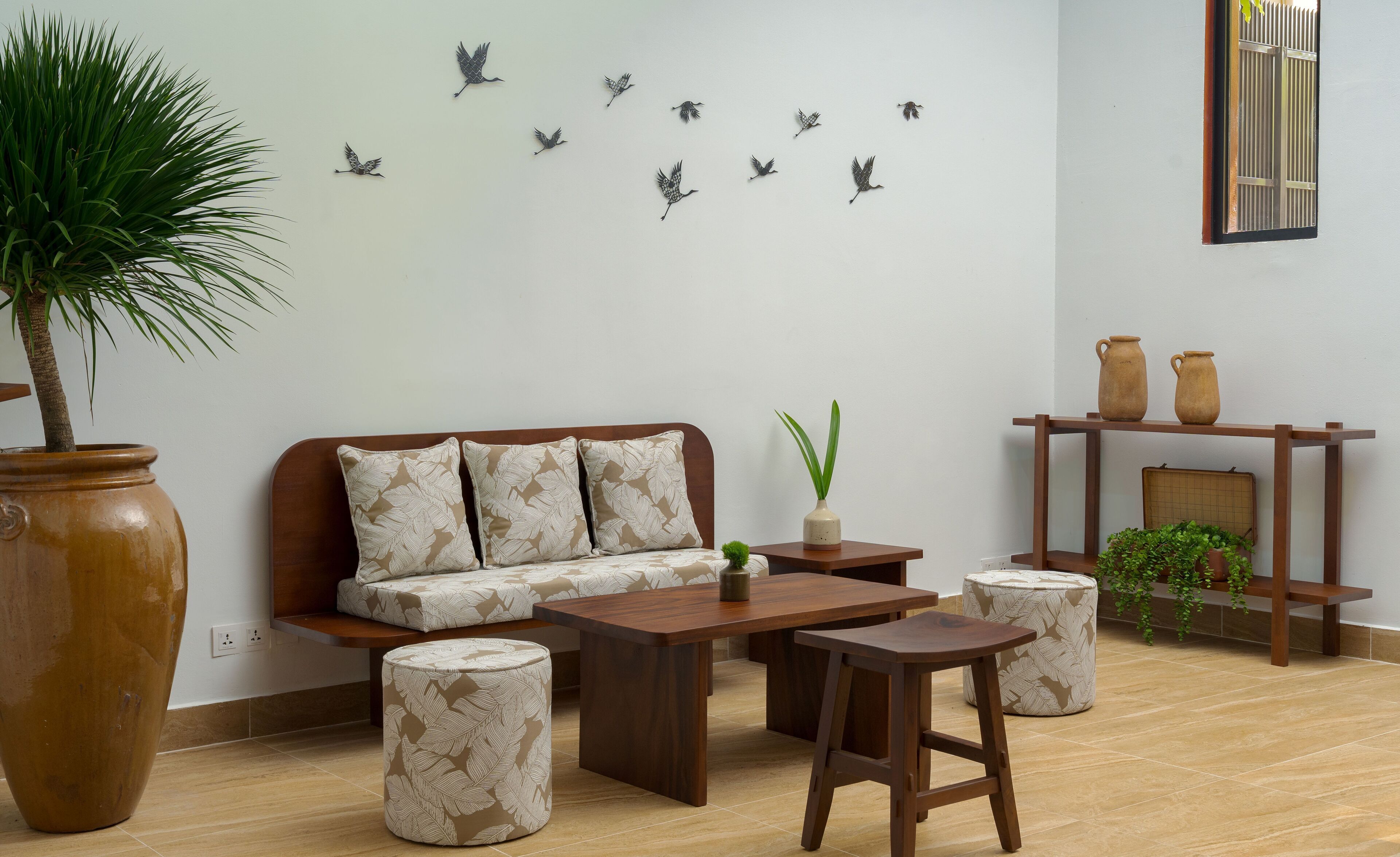 Ein Wohnzimmer mit Sofa, Couchtisch, Hocker und einer Wand mit Vogelmotiven.