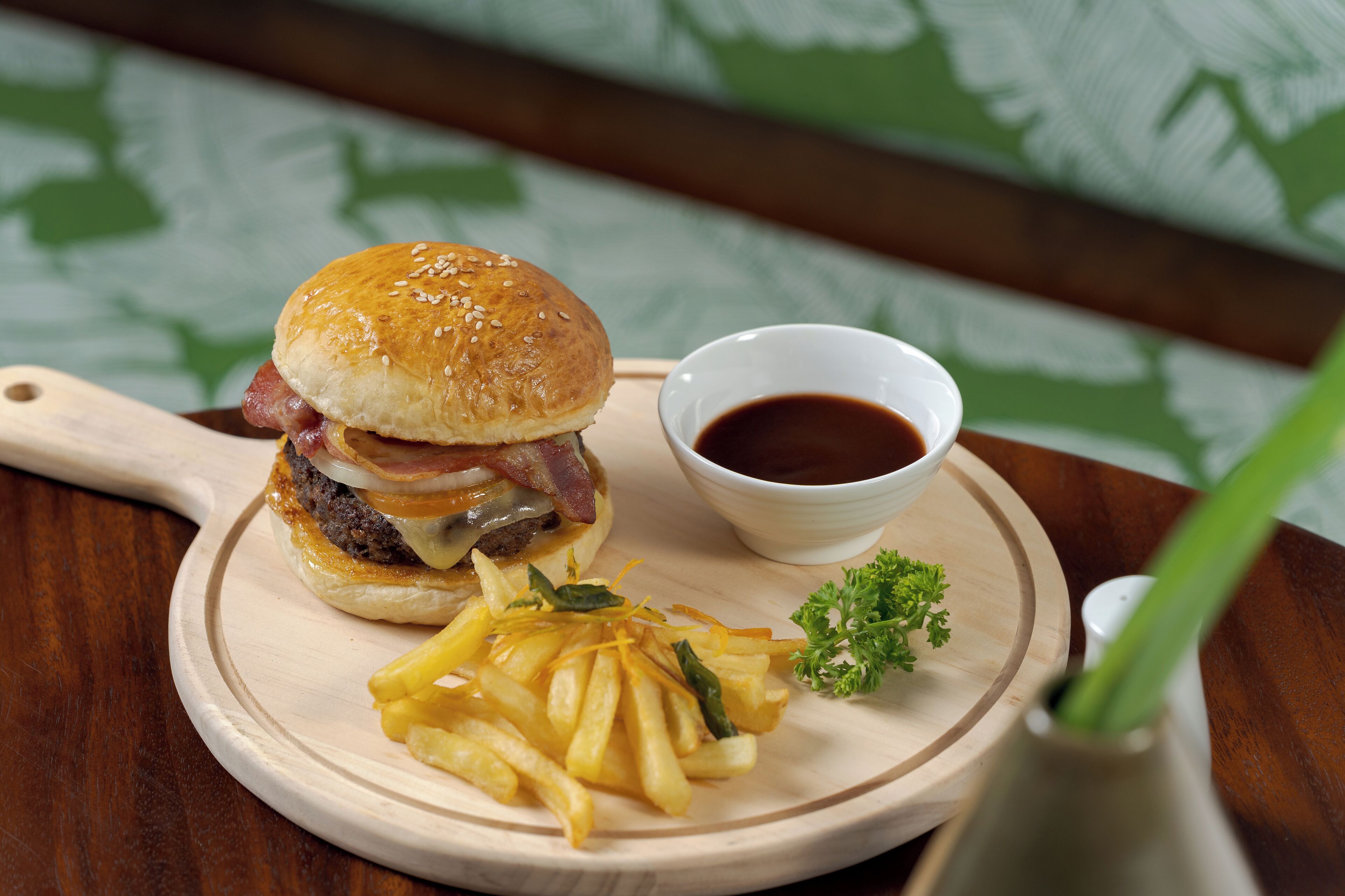 Hamburguesa con papas fritas y una salsa en una tabla de madera.