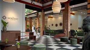 Eine Hotellobby mit Schachbrettfußboden, Holztischen, grün gepolsterten Sitzgelegenheiten und einer Buddha-Statue.