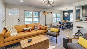 A spacious living room with a leather sofa, wooden coffee table, and a dining area with a table and chairs. - Dog-Friendly Dallas Home w/ Fenced Yard! (Dallas)