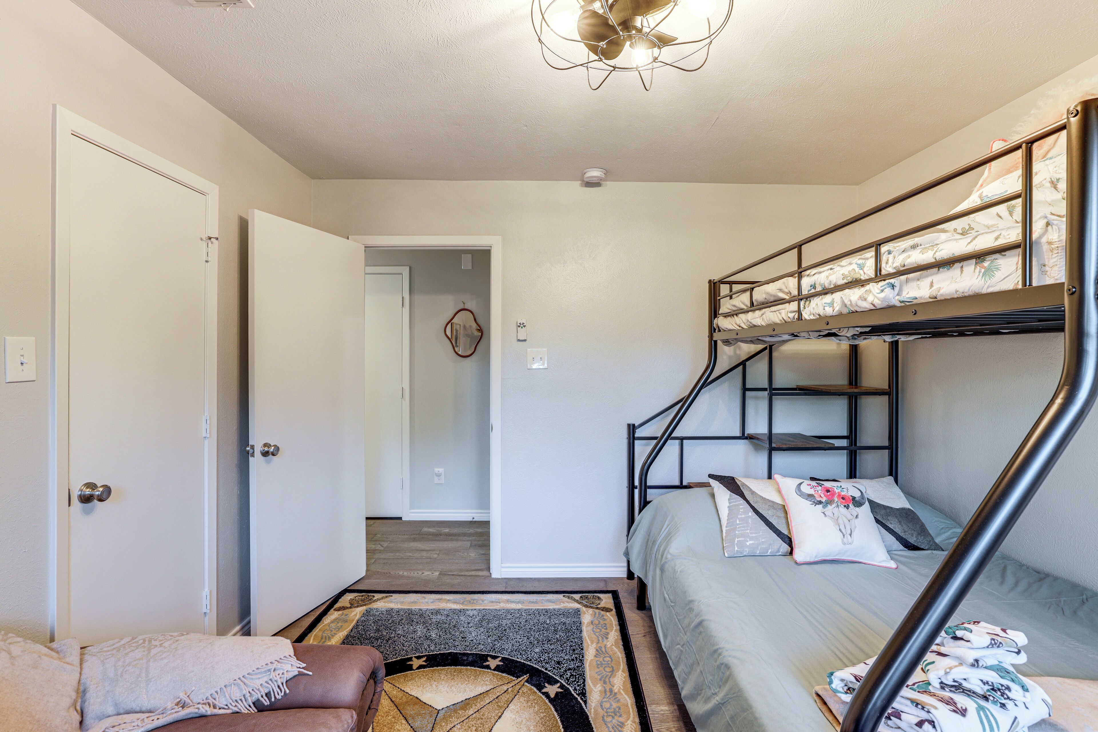 A compact room with a bunk bed, a sofa, and a door leading to another room.
