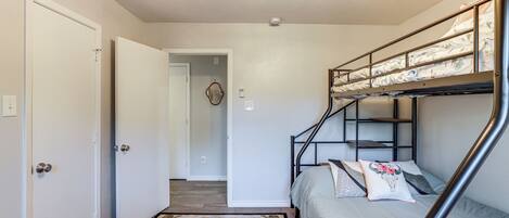 A compact room with a bunk bed, a sofa, and a door leading to another room.